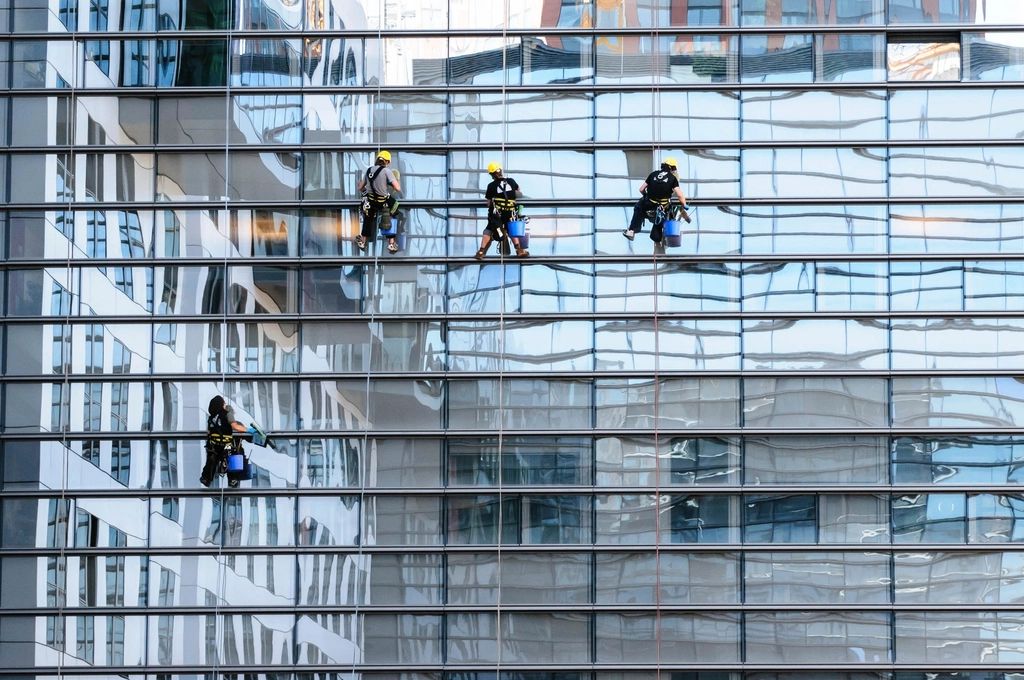 Rope-access technicians cleaning the glass facade of a high-rise building
